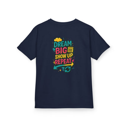 Navy blue kids tee featuring colorful text: "Dream Big. Show Up. Repeat." motivational design for back-to-school.