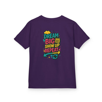 Purple kids tee featuring motivational message: Dream Big. Show Up. Repeat. Ideal for back-to-school confidence.