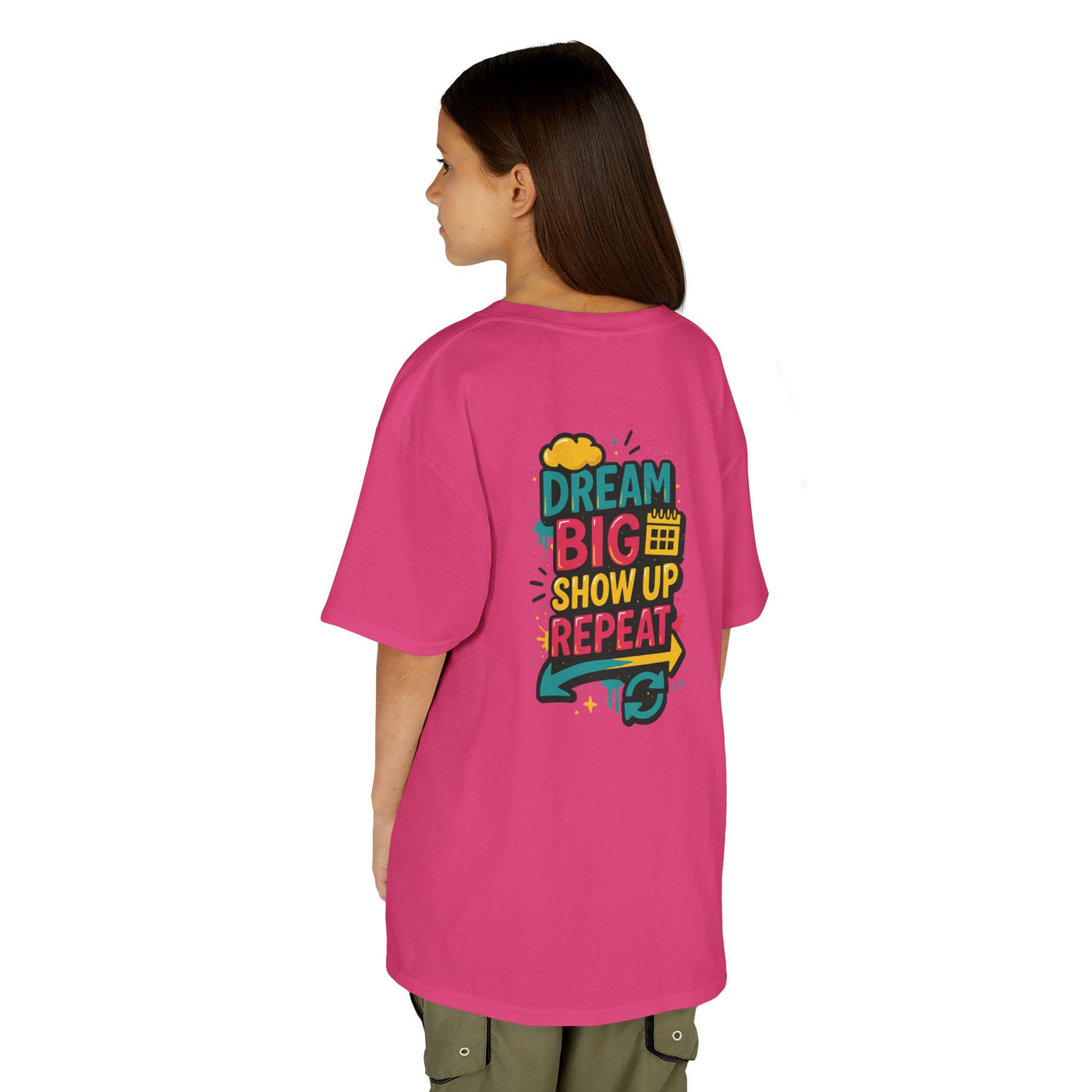 Back view of a kid wearing a pink motivational tee saying "Dream Big. Show Up. Repeat." perfect for back-to-school.