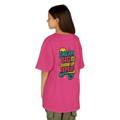 Back view of a kid wearing a pink motivational tee saying "Dream Big. Show Up. Repeat." perfect for back-to-school.