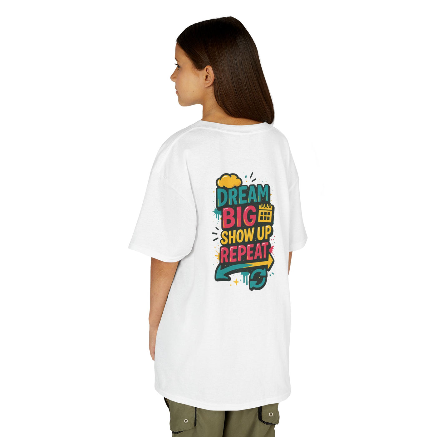 Girl wearing white motivational tee with 'Dream Big. Show Up. Repeat.' design on back, ideal for back-to-school inspiration.