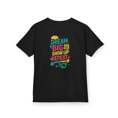 Black kids tee featuring colorful text: 'Dream Big. Show Up. Repeat.' for motivational back-to-school style.