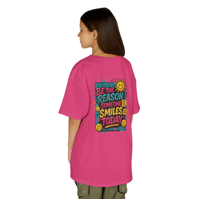 Kids' back view of pink Be The Reason Someone Smiles Today motivational tee with cheerful sun graphic.