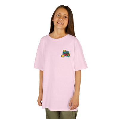 Kid wearing a pink motivational tee that says 'Dream Big. Show Up. Repeat.' perfect for back-to-school.