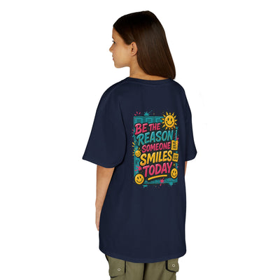 Child wearing a navy t-shirt with colorful 'Be The Reason Someone Smiles Today' graphic on the back.