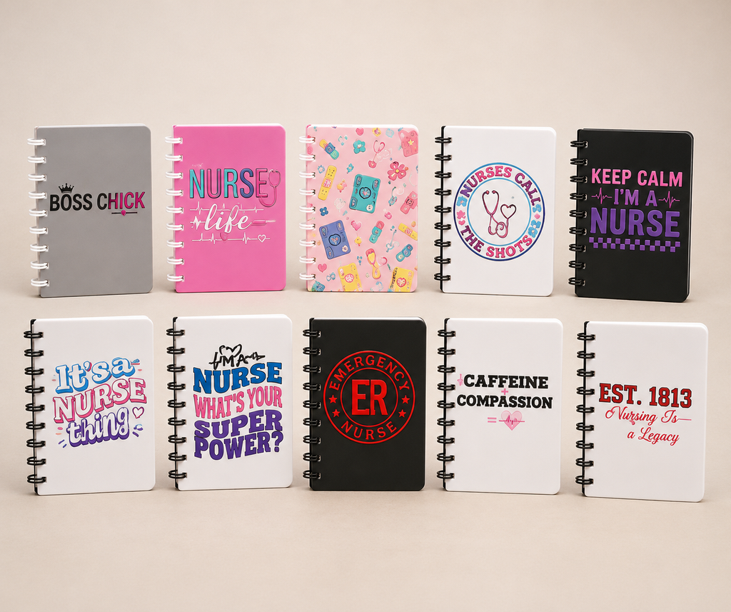 Eight spiral-bound notebooks arranged in two rows on a light beige background. The notebooks feature various colorful and monochrome designs with nurse-themed quotes and graphics, including 'BOSS CHICK', 'NURSE like', 'NURSES CAN'T BE SHOT!', 'KEEP CALM I'M A NURSE', 'It's a NURSE thing!', 'NURSE WHAT'S YOUR SUPER POWER?', 'EMERGENCY ROOM NURSE', and 'CAFFEINE COMPASSION' and 'EST.