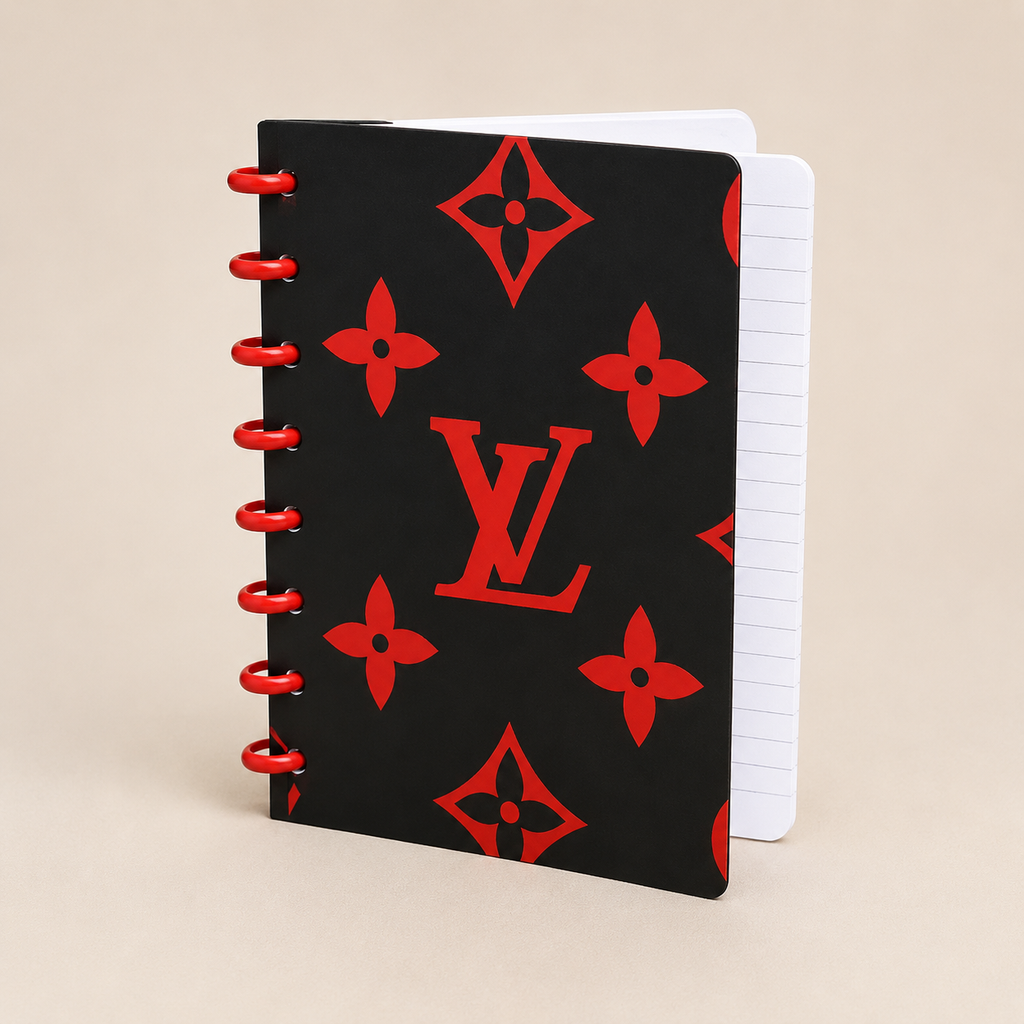 A black spiral-bound notebook with a red Louis Vuitton monogram pattern and red wire binding, shown on a light beige background.