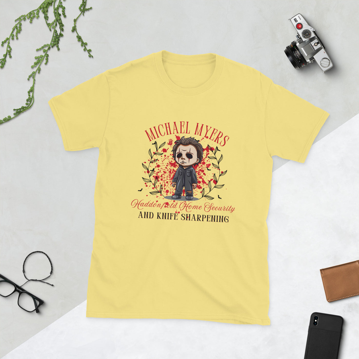 Michael Myers Halloween t-shirt with cartoon graphic, featuring home security and knife sharpening theme, on a yellow background.